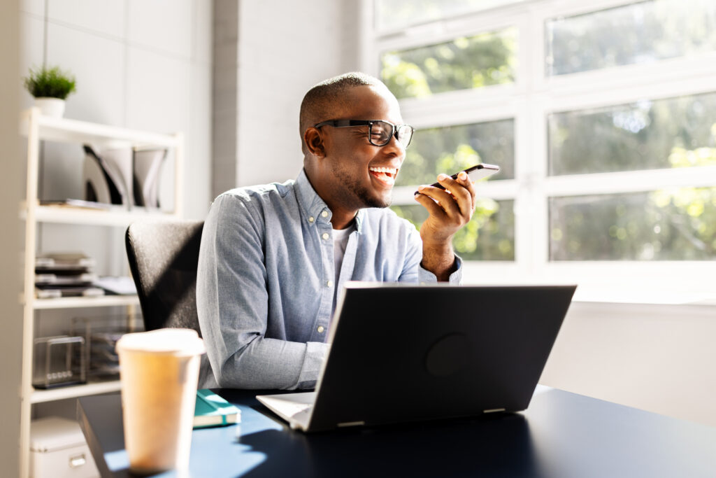 Los Angeles Account executive talking on speaker phone seen laughing at desk in front of windows