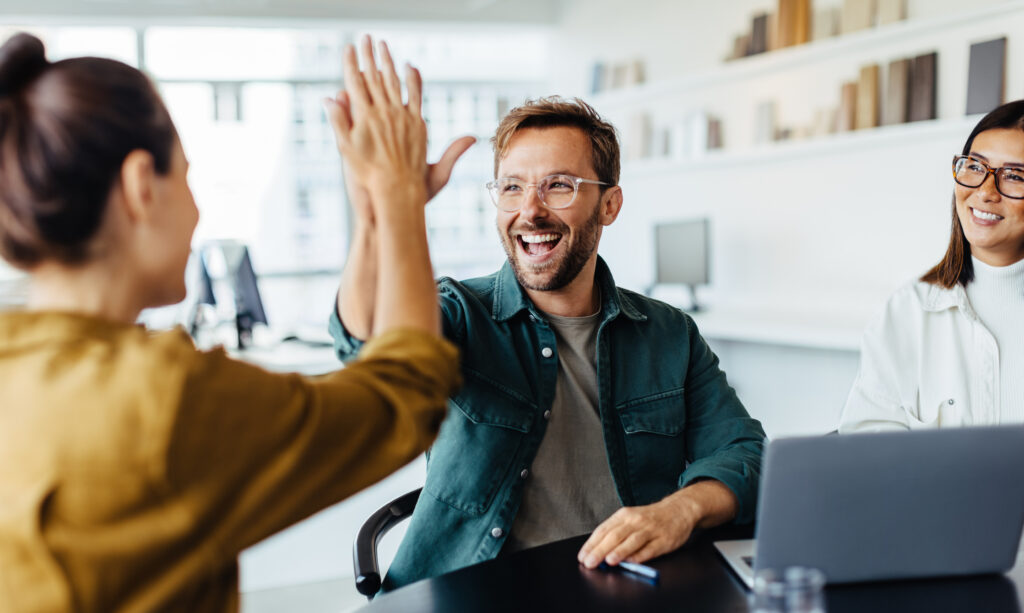 LA Account executives at a conference table high five in celebration after selling a deal