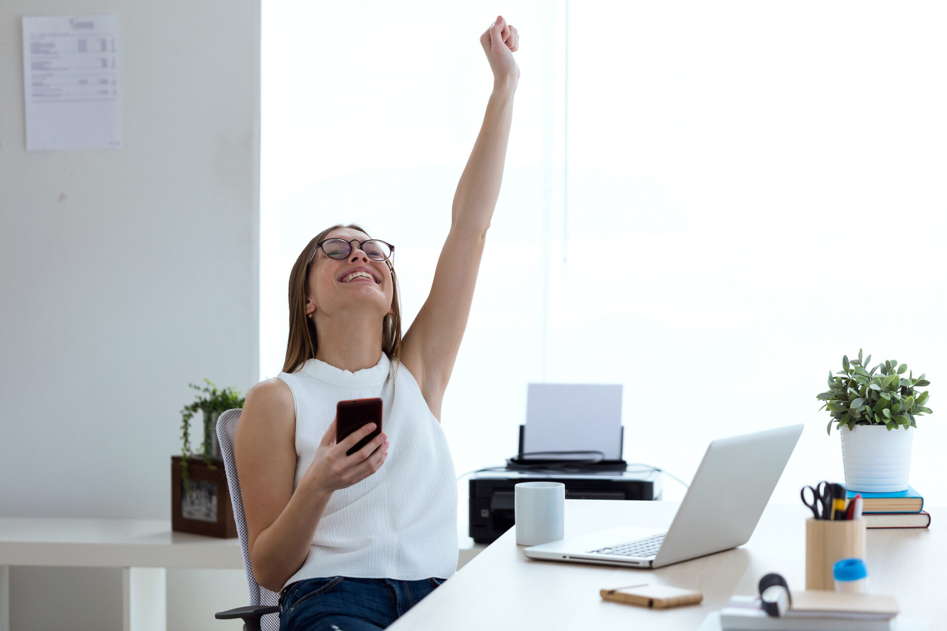 AccountMakers staff business woman is seen celebrating a sales victory with a hand in the air at a desk