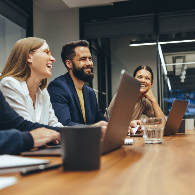 Immediate Temporary and Direct-Hire Sales Staffing Image of a group of colleagues in a meeting laughing and smiling in discussion