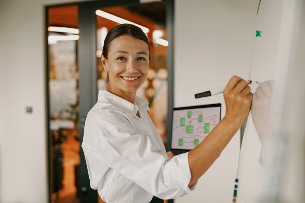 Business development manager writes on a board while recruiting LA BDRs and is smiling