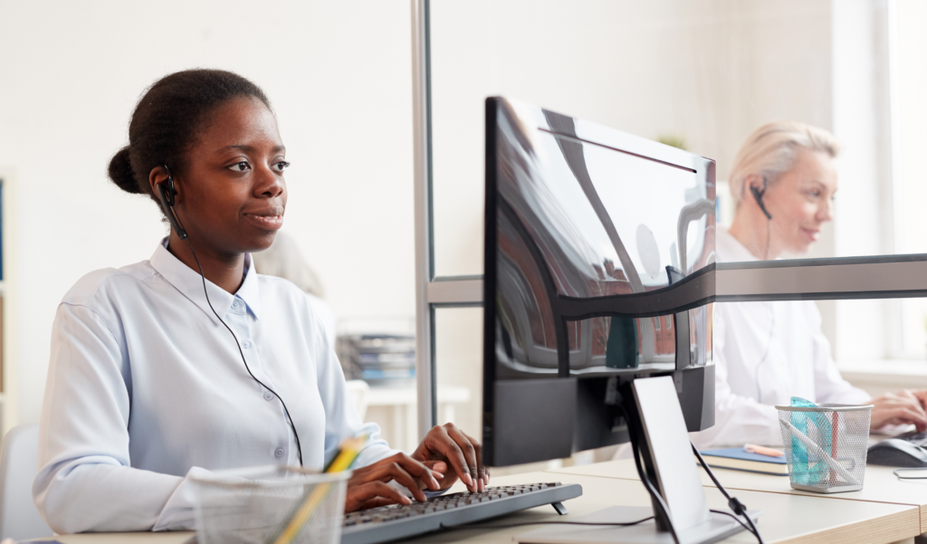 Temp Customer Support Hiring - image of modern customer support specialist sitting at desk working on computer with headset in