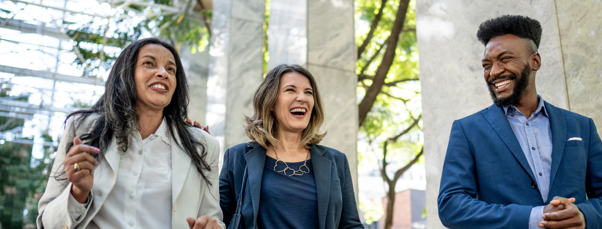 Three coworkers smiling and talking while walking outdoors between client drop-in meetings.