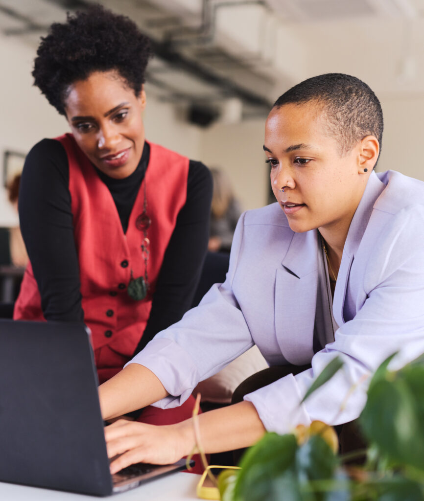 Two customer success professionals reviewing account data and onboarding workflows on a laptop, representing AccountMakers' hiring and recruiting for customer success roles focused on client retention and growth.