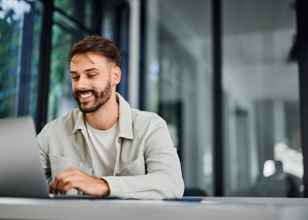 Customer service professional working on a laptop in a modern office, representing how AccountMakers connects employers with experienced support talent focused on resolving customer needs and delivering high-quality service.