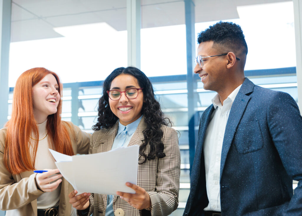 Call center sales representatives collaborating on sales goals and performance metrics, and participating in a coaching discussion in a modern office.