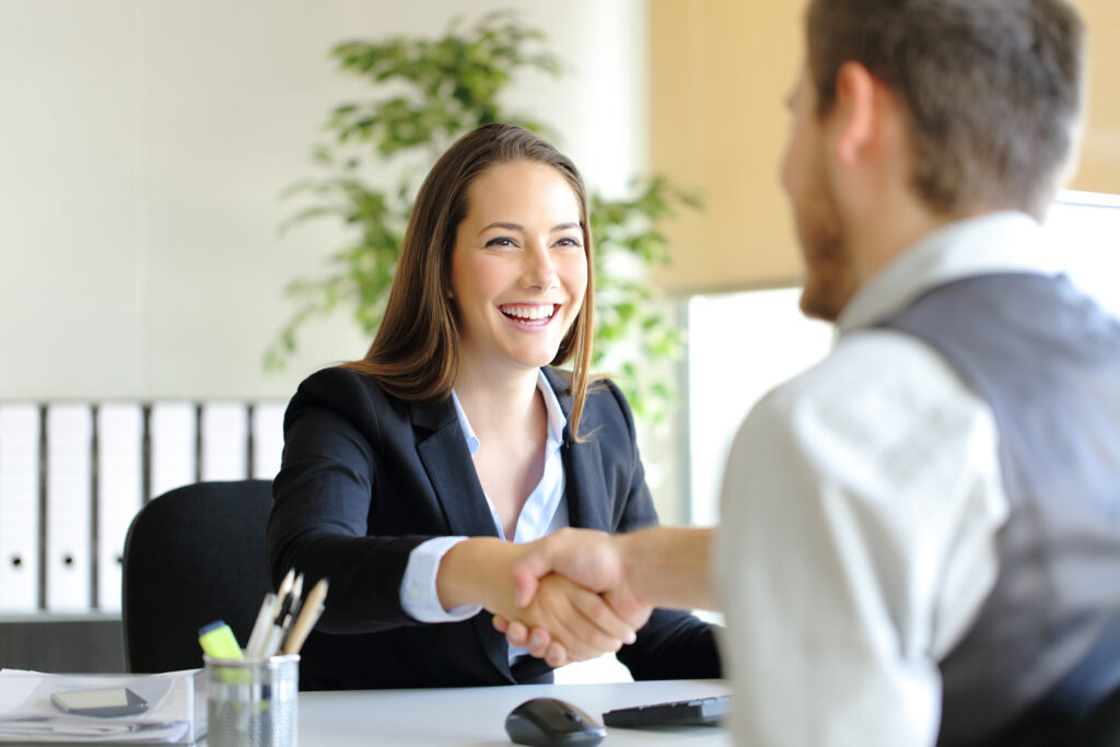 A new sales tip is shared during a sales meeting. A women sales professional is seen shaking hands with a new sales candidate for a sales job.